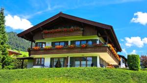 a house with flower boxes on top of a hill at Ferienwohnung Rosendahl in Reit im Winkl