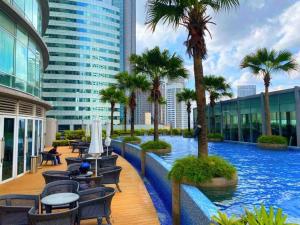 una piscina en un edificio con palmeras y sillas en Vortex Suites KL City Center, en Kuala Lumpur