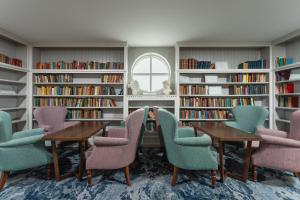 a library with a table and chairs and bookshelves at Connemara Coast Hotel in Furbo