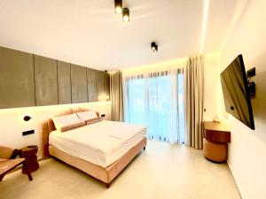 a bedroom with a bed and a large window at Tramonto Maisonettes & Suites in Parga