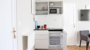 una pequeña cocina con armarios blancos y microondas en Park and Bike City Studio Zagreb, en Zagreb