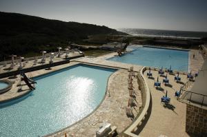 two swimming pools with chairs and the ocean in the background at Sintra Sol - Apartamentos Turisticos in Sintra