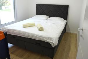 a bed with a black headboard and two towels on it at Holiday Home Maslina in Široki Brijeg