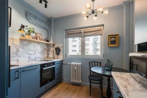 a kitchen with blue cabinets and a table and a window at Cozy Urban Studio Piata Victoriei in Floreasca