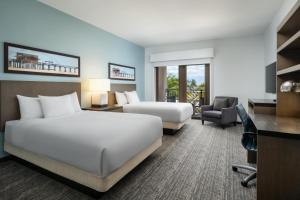 a hotel room with two beds and a desk at Hyatt House Naples 5th Avenue in Naples