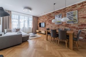 a dining room and living room with a brick wall at Kochanowskiego Luxury Apartment by BookingHost in Poznań