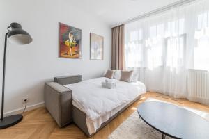a white bedroom with a bed and a glass table at Kochanowskiego Luxury Apartment by BookingHost in Poznań
