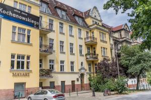 a yellow building with a car parked in front of it at Kochanowskiego Luxury Apartment by BookingHost in Poznań