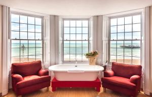 a bathroom with two red chairs and a bath tub at Drakes Hotel in Brighton & Hove