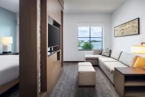 a hotel room with a couch and a tv at Hyatt House Naples 5th Avenue in Naples