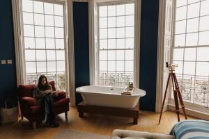 a woman sitting in a chair next to a tub in a bathroom at Drakes Hotel in Brighton & Hove