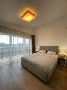 a bedroom with a bed and a large window at Kotedzas Sventojoje 11 Gulbiu in Šventoji