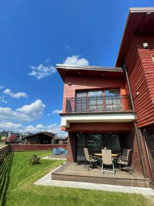 a house with a table and chairs on a deck at Kotedzas Sventojoje 11 Gulbiu in Šventoji