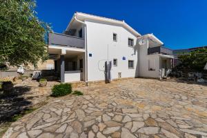a white house with a stone driveway at Apartments Crnko, 50m from the beach with free parking and drinkable tap water in Vir