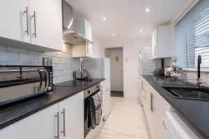 a kitchen with white cabinets and black counter tops at The Imeary - Vacant Nests in Westoe