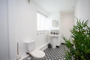 a white bathroom with a toilet and a sink at The Imeary - Vacant Nests in Westoe +37 photos