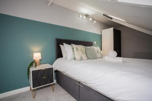 a bedroom with a large bed with a blue wall at The Imeary - Vacant Nests in Westoe