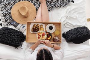 a woman laying on a bed with a tray of food at Naxos Earth Suites in Mikri Vigla