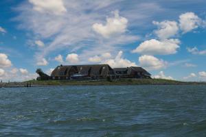 a large house on an island in the water at Gästehaus Bi de Ley in Langeneß