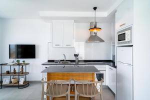 Una cocina con gabinetes blancos y una mesa con sillas. en Terrazas de Ladera A2 Luxury by Casasol, en Nerja