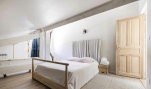 ein weißes Schlafzimmer mit einem Bett und einer Tür in der Unterkunft Loft Frontière Montagne et Plage in Urrugne