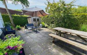 a patio with a wooden bench and an umbrella at Stunning Stacaravan In Tzummarum in Tzummarum +12 photos