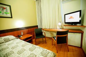 um quarto de hotel com uma cama, uma secretária e uma televisão em Eston Hotel - LOCALIZAÇÃO CENTRAL PRIVILEGIADA -PET FRIENDLY em Chapecó