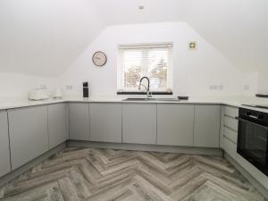 a kitchen with white cabinets and a sink at Sea View in South Hayling +21 photos