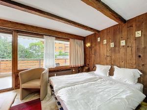 a bedroom with a bed and a chair and a window at Cimerose 1 in Verbier