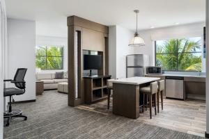 an open kitchen and living room with a table and chairs at Hyatt House Naples 5th Avenue in Naples