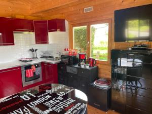 The Cabin with heated outdoor pool في Chalandrey: مطبخ مع أجهزة حمراء وسوداء في الغرفة +6 صور