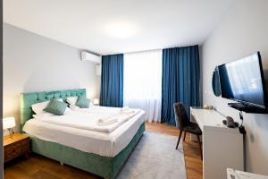 a bedroom with a bed and a desk and a television at La Mansión in Lozenets