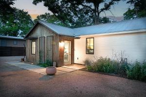 een klein wit huis met een deur in een tuin bij Cava House, Hot tub, Cowboy Pool, Fire pit! in Fredericksburg