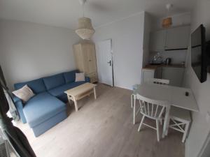 a living room with a blue couch and a table at Domek na Błotach in Karwieńskie Błoto Drugie