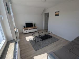uma sala de estar com um sofá e uma TV em Wohnung am Fischereihafen Modern & gemütlich em Bremerhaven