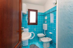 ein blau gefliestes Bad mit 2 WCs und einem Waschbecken in der Unterkunft Sea View - Cozy apartment with parking space in San Teodoro