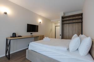 a bedroom with a white bed and a television at Aqua Batumi Hotel & Apartments in Batumi