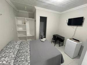 a bedroom with a bed and a desk and a television at Villa Beira Mar Suítes in Fortaleza