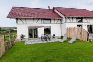 a white house with a table and chairs and an umbrella at Binzighof Ferienhäuser in Oberkirch