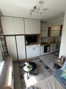 eine Küche mit weißen Schränken und einem Tisch im Zimmer in der Unterkunft Mieszkanko w Perle Mazur-Ostroda in Ostróda