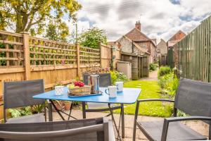 a table and chairs in a backyard with a fence at Sherbet Cottage in South Creake