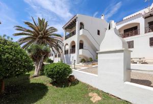 a white house with a palm tree in front of it at Apartament Cargol in Es Mercadal
