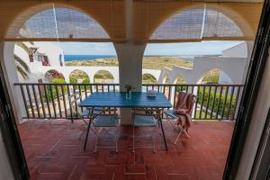 a patio with a blue table and chairs on a balcony at Apartament Cargol in Es Mercadal