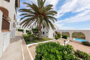 an exterior view of a villa with a palm tree at Apartament Cargol in Es Mercadal +9 photos