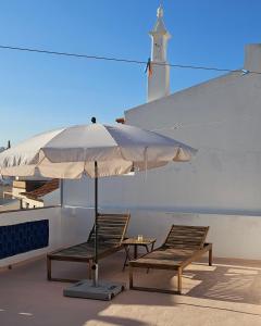 un par de sillas y un paraguas en el techo en Casinha das Portas do Mar, en Armação de Pêra