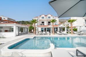 een zwembad voor een huis met palmbomen bij Luxury beachfront Villa Providenca in Podstrana
