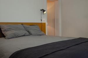 ein Bett mit zwei Kissen und einer Lampe an der Wand in der Unterkunft Cosy one bedroom close to Paris & Stade de France in Saint-Denis