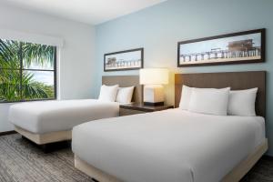 a hotel room with two beds and a window at Hyatt House Naples 5th Avenue in Naples