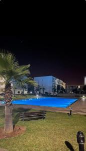 una palma e una piscina di notte di Appartement de Luxe à Bahia Golf Beach Spacieux de 126 m a Bouznika
