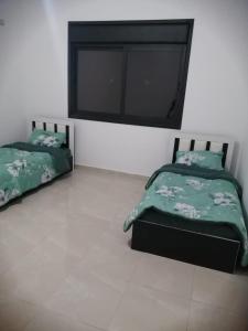 Un dormitorio con dos camas y un televisor de pantalla plana. en Villa Al ulaa, en Māḩiş